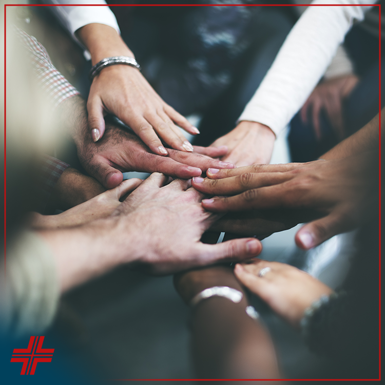 A group of diverse hands stacked together in the center, symbolizing teamwork and unity. A red medical cross symbol appears in the lower left corner of the image. | California Urgent Care Center